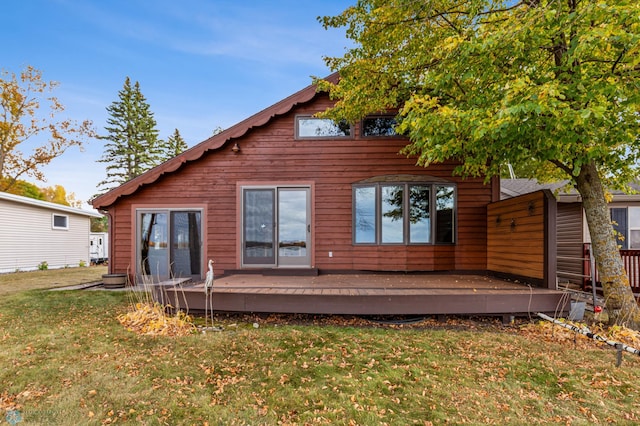 back of property with a deck and a lawn