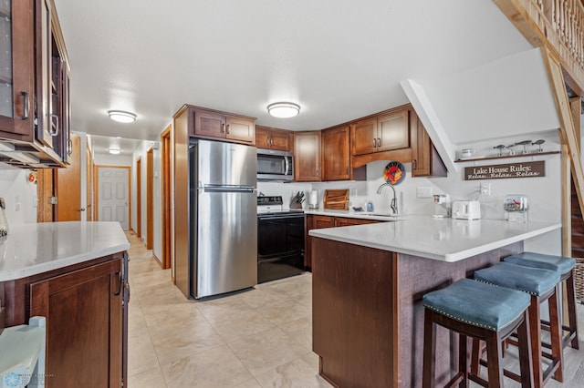 kitchen featuring a breakfast bar area, stainless steel appliances, sink, and kitchen peninsula