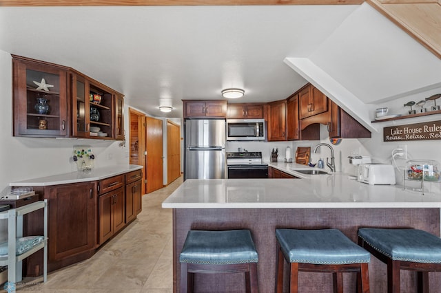 kitchen featuring a breakfast bar, beverage cooler, sink, kitchen peninsula, and appliances with stainless steel finishes