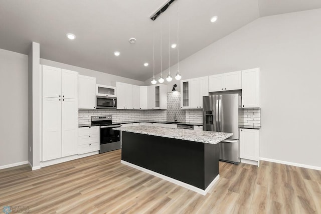 kitchen with decorative backsplash, a kitchen island, light hardwood / wood-style flooring, pendant lighting, and stainless steel appliances