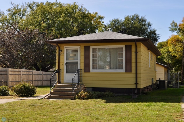 bungalow-style home with cooling unit and a front lawn