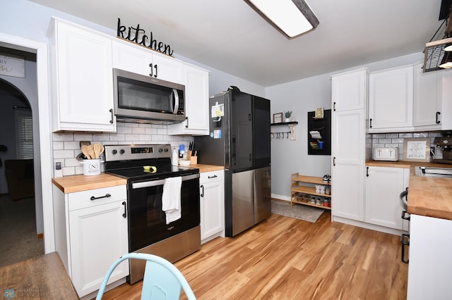 kitchen with white cabinets, stainless steel appliances, decorative backsplash, and wooden counters