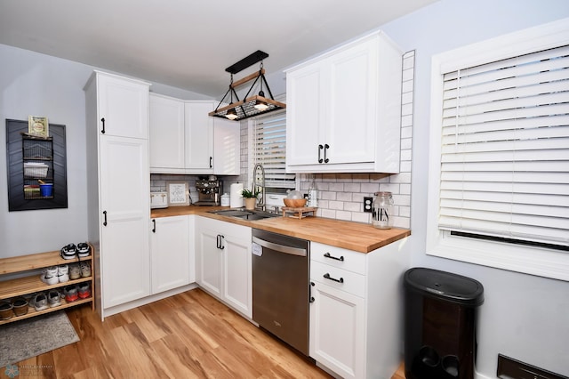 kitchen with decorative backsplash, wood counters, sink, stainless steel dishwasher, and white cabinets