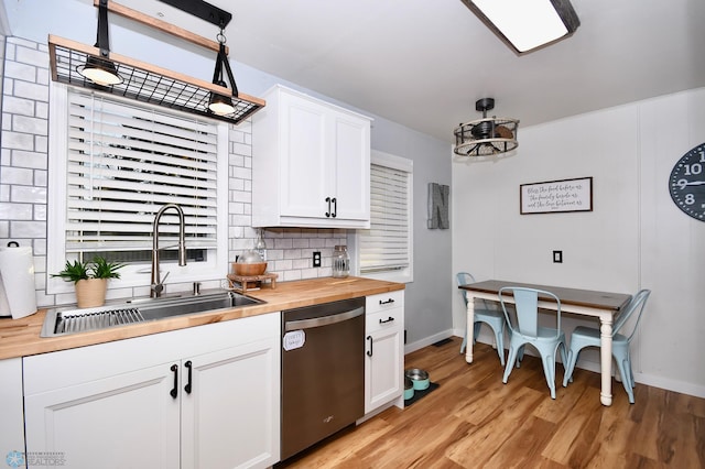 kitchen with butcher block countertops, dishwasher, white cabinets, and decorative light fixtures