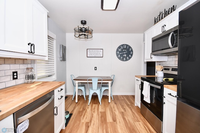 kitchen featuring white cabinets, stainless steel appliances, backsplash, and butcher block countertops