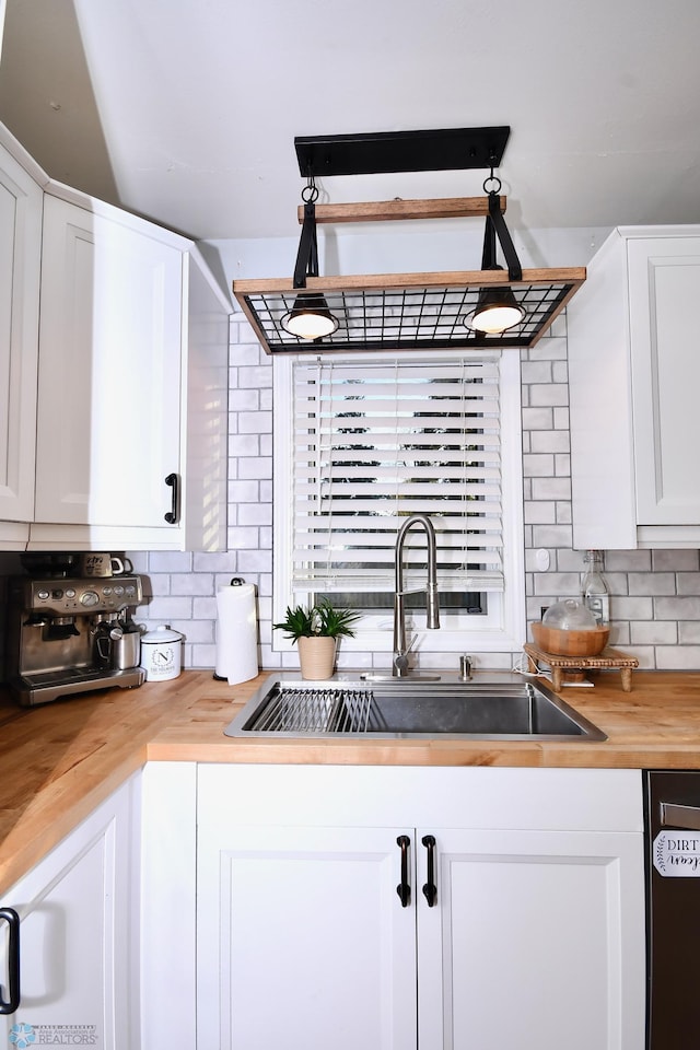 kitchen featuring decorative backsplash, dishwasher, wood counters, sink, and white cabinets