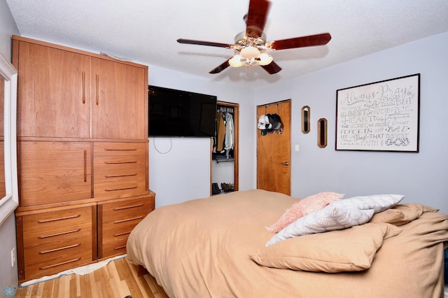 bedroom featuring light hardwood / wood-style floors, a textured ceiling, and ceiling fan