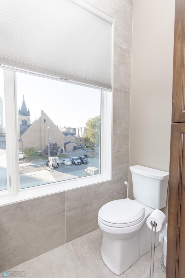 bathroom with toilet, tile walls, and tile patterned flooring