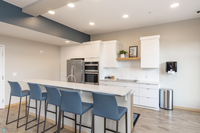 kitchen featuring light hardwood / wood-style floors, stainless steel appliances, a breakfast bar, and white cabinets