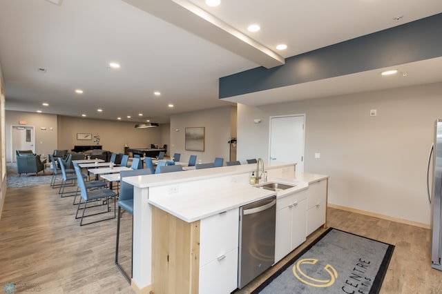 kitchen with light hardwood / wood-style flooring, stainless steel appliances, sink, and a kitchen island with sink