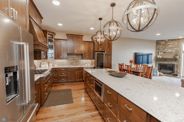 kitchen with appliances with stainless steel finishes, an inviting chandelier, light hardwood / wood-style flooring, sink, and decorative light fixtures