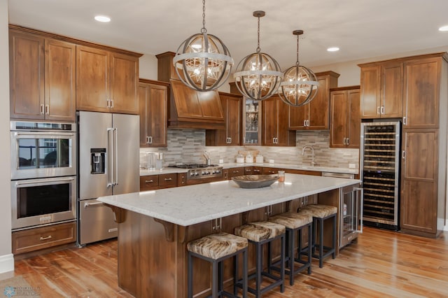 kitchen featuring beverage cooler, appliances with stainless steel finishes, light wood-type flooring, custom range hood, and a center island