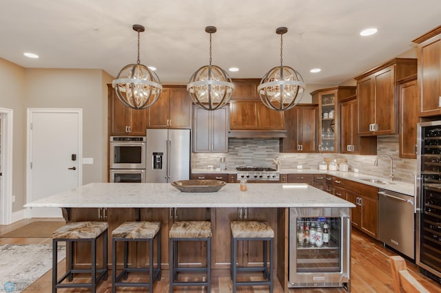 kitchen featuring a center island, stainless steel appliances, light hardwood / wood-style floors, and beverage cooler