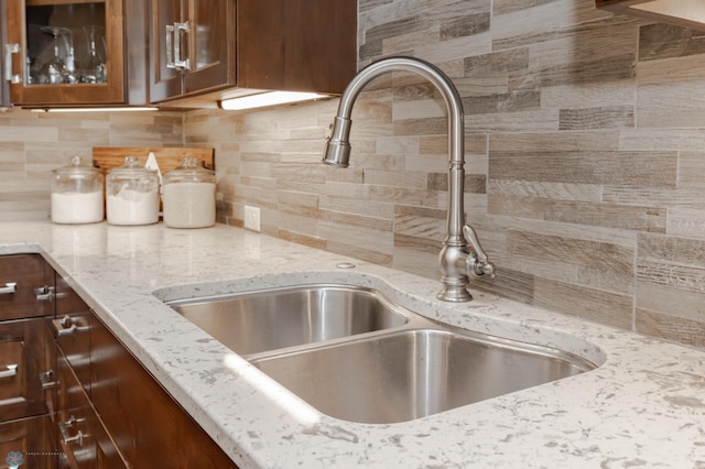 details with decorative backsplash, light stone countertops, and sink