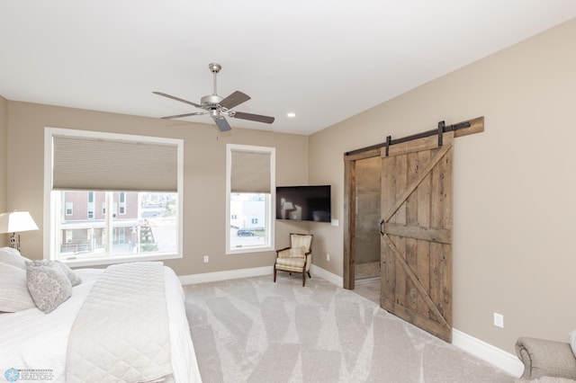 carpeted bedroom with a barn door and ceiling fan