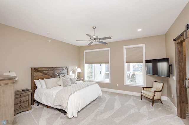 bedroom with a barn door, light colored carpet, and ceiling fan