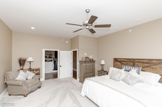 carpeted bedroom featuring a walk in closet, a closet, and ceiling fan