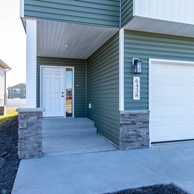 view of exterior entry with a garage and central air condition unit