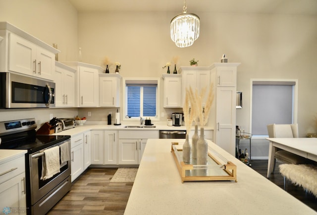 kitchen featuring appliances with stainless steel finishes, sink, dark hardwood / wood-style flooring, pendant lighting, and white cabinets