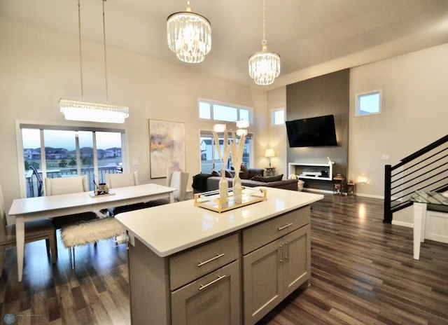 kitchen with a kitchen island, a high ceiling, pendant lighting, gray cabinets, and dark hardwood / wood-style flooring