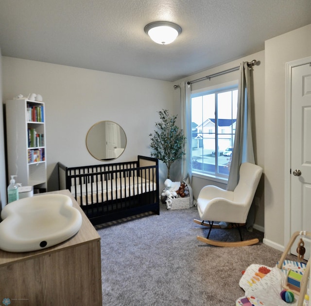 carpeted bedroom with a textured ceiling and a crib