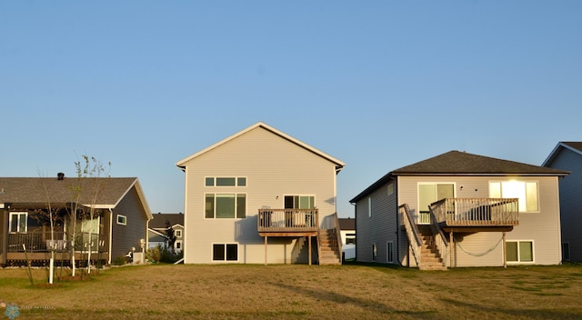 rear view of property featuring a wooden deck and a lawn