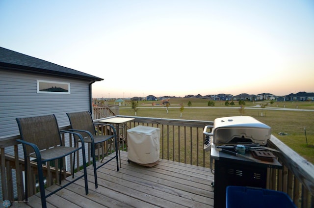 deck at dusk with a lawn and grilling area