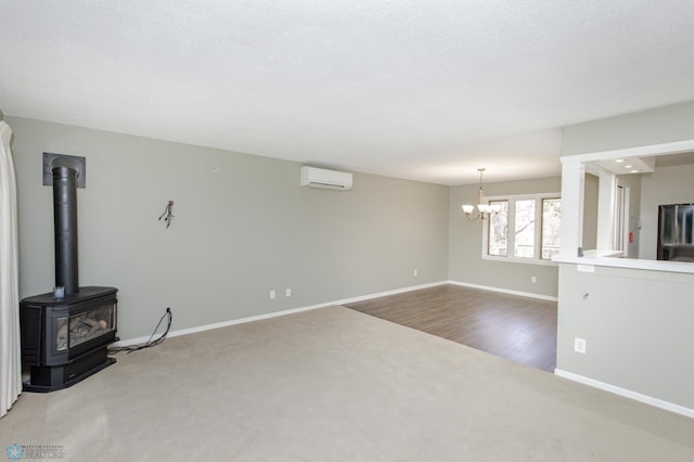 unfurnished living room featuring wood-type flooring, an AC wall unit, a textured ceiling, a wood stove, and a notable chandelier