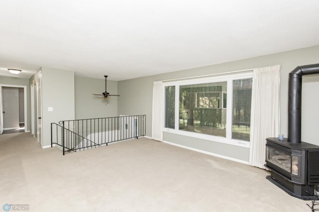 carpeted living room featuring ceiling fan and a wood stove