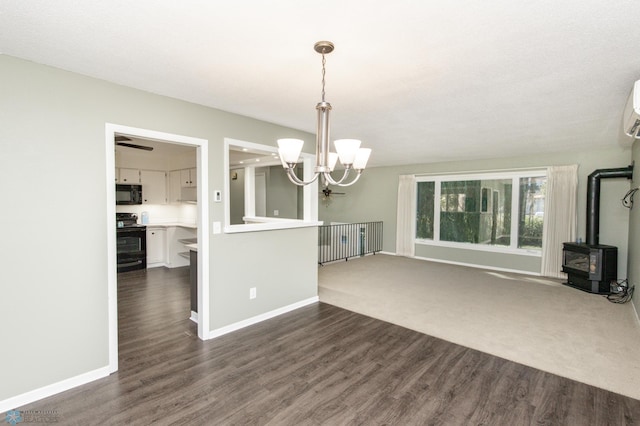 unfurnished living room featuring an AC wall unit, a notable chandelier, dark hardwood / wood-style floors, and a wood stove