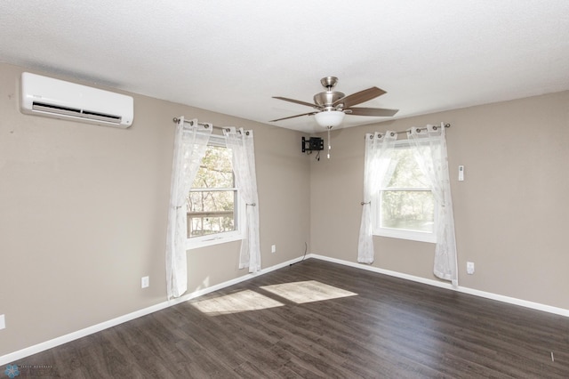 spare room featuring a wall unit AC, a textured ceiling, ceiling fan, and dark hardwood / wood-style flooring