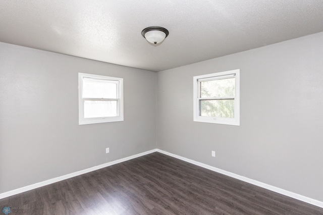 spare room featuring a textured ceiling and dark hardwood / wood-style flooring