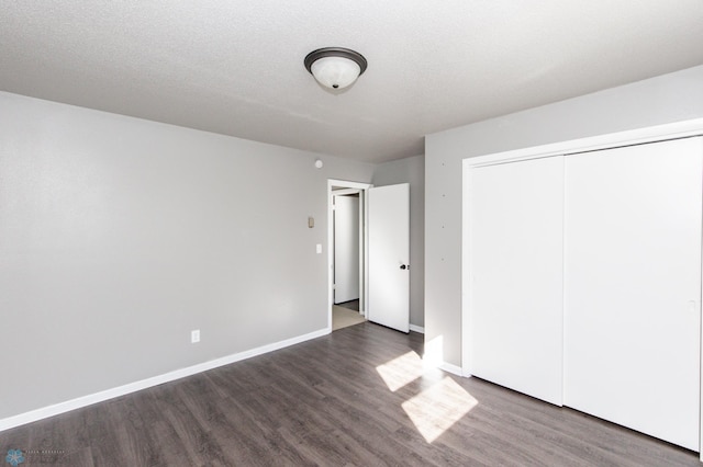 unfurnished bedroom with a textured ceiling, a closet, and dark hardwood / wood-style flooring