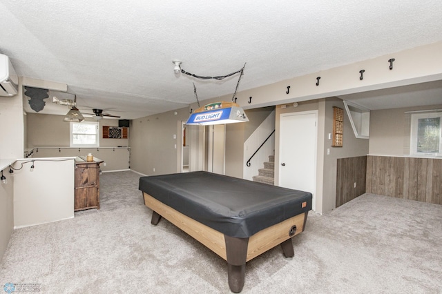 recreation room with a textured ceiling, wooden walls, carpet, and ceiling fan