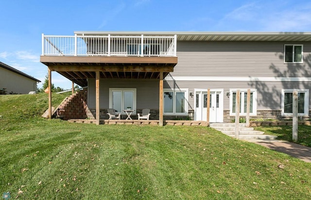 rear view of house featuring a patio, a wooden deck, and a lawn