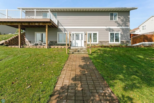 rear view of property featuring a wooden deck and a lawn