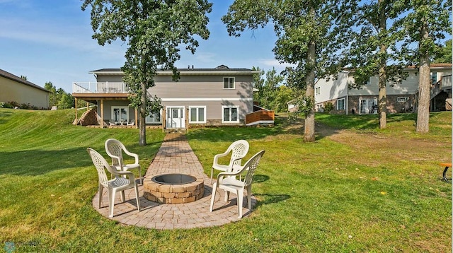 rear view of property featuring a patio area, a lawn, and a fire pit