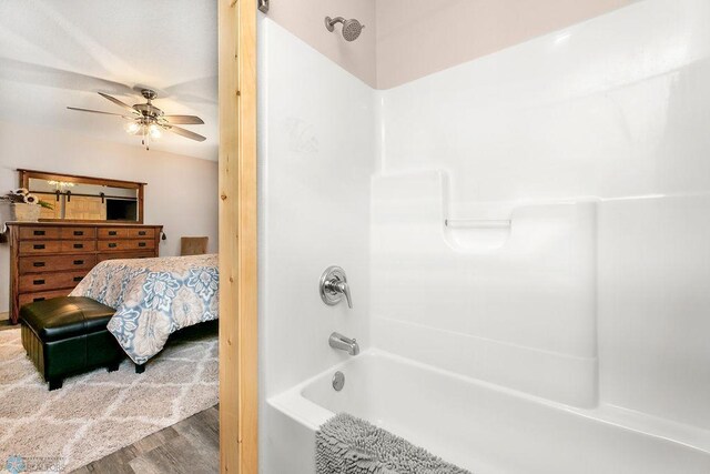 bathroom featuring shower / washtub combination, hardwood / wood-style floors, and ceiling fan