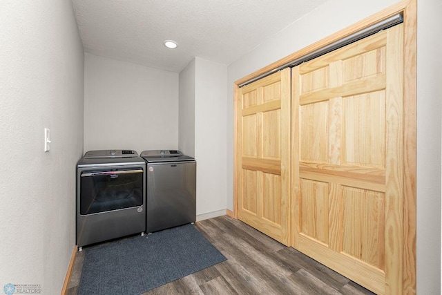 washroom with dark wood-type flooring, washing machine and dryer, and a textured ceiling