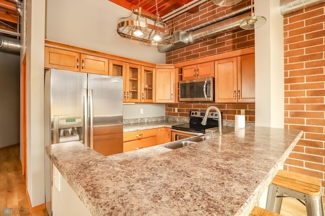 kitchen featuring kitchen peninsula, appliances with stainless steel finishes, a breakfast bar, light hardwood / wood-style flooring, and sink