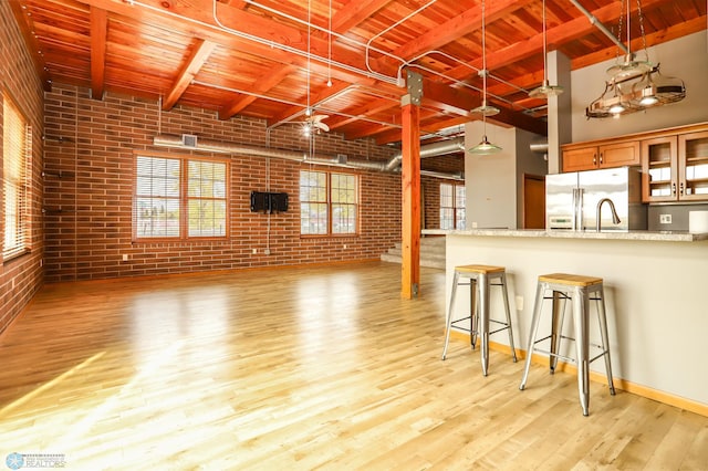 kitchen with brick wall, light stone countertops, and light wood-type flooring