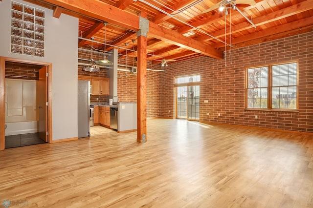 unfurnished living room with wood ceiling, light hardwood / wood-style flooring, beamed ceiling, a high ceiling, and brick wall