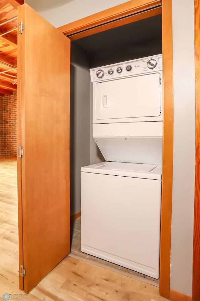 clothes washing area with stacked washer / drying machine and light hardwood / wood-style flooring