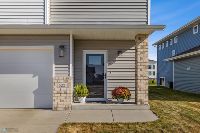 view of exterior entry with a lawn and a garage