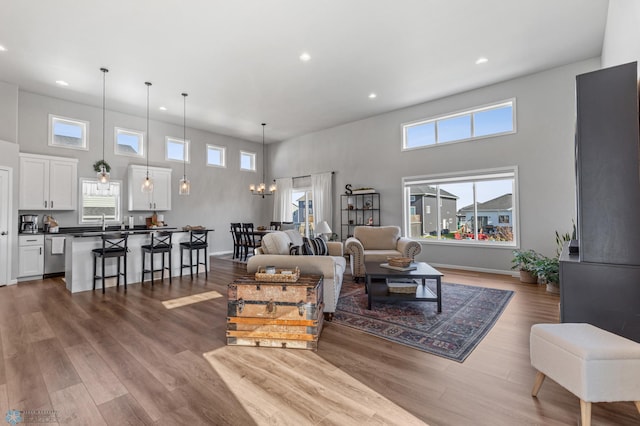 living room featuring a chandelier, wood-type flooring, and a towering ceiling