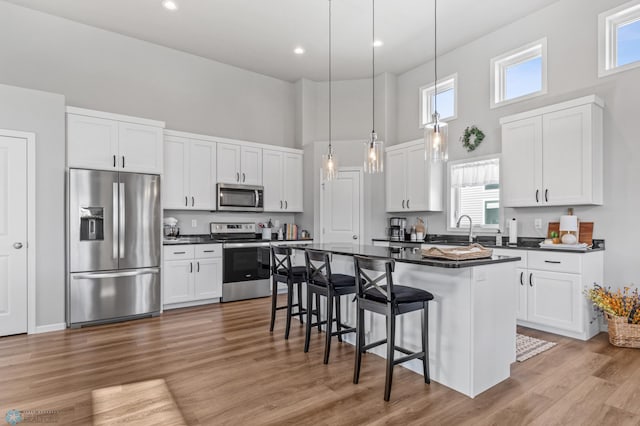 kitchen featuring a healthy amount of sunlight, appliances with stainless steel finishes, a high ceiling, and white cabinets