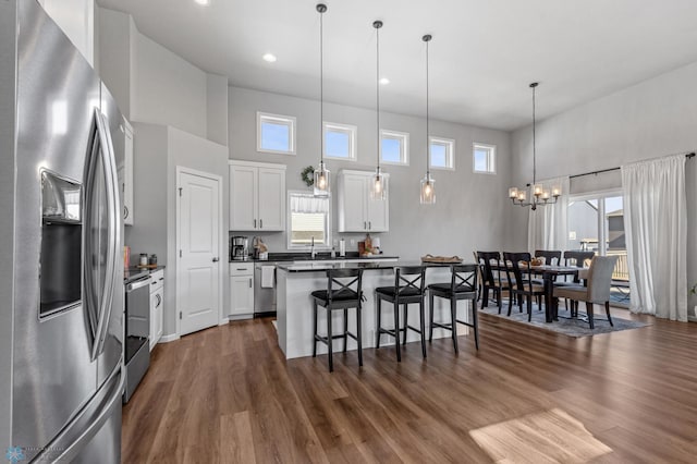 kitchen with appliances with stainless steel finishes, white cabinetry, dark wood-type flooring, and a wealth of natural light