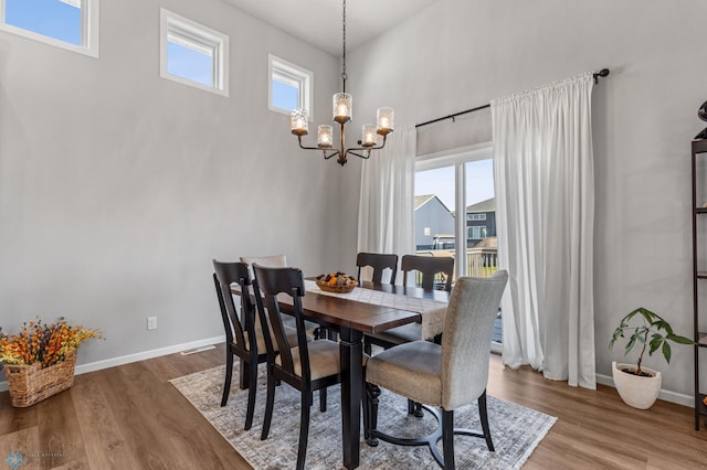 dining space with a notable chandelier, a healthy amount of sunlight, and wood-type flooring