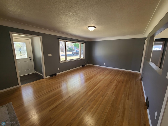 spare room with crown molding, hardwood / wood-style floors, and a textured ceiling