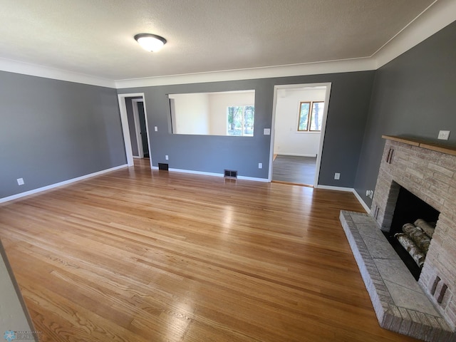 unfurnished living room with a textured ceiling, light hardwood / wood-style flooring, and a fireplace